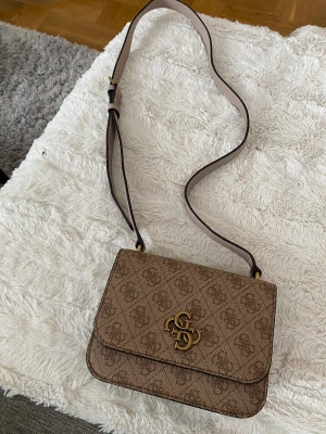 Guess väska - Köptes för 2 år sedan! Väldigt sparsamt använd då det inte riktigt är min färg Rymlig med ett litet fack och justerbart band 