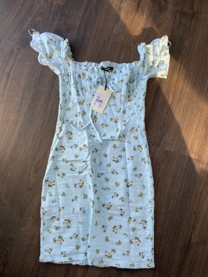 Blommig klänning  - En kort blå blommig klänning från BikBok, storlek S. Aldrig använd så prislappen är kvar! Stretchig i materialet bak. ❤️