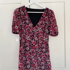 Blommig klänning - En rosa röd blommig midi klänning i två lager med puffärm.  Superfin men säljer då underkjolen är alldelles för kort för mig som är 174