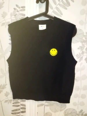 Svart väst  - Svart väst med en Smiley från Hm  Med märket SMILEY Storlek xs men passar s också