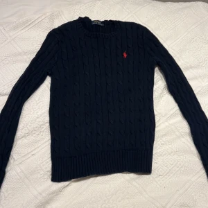 Ralp Lauren kabelstickad tröja - Marinblå kabelstickad tröja från Ralph Lauren med rött märke