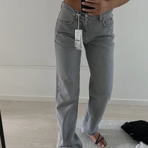 Gråa Low Waist Jeans - Lågmidjade, raka jeans från Gina tricot. Innebensömmen är 82cm i Stl 38, detta är Stl 34. De är uppsydda ca 1cm men allt tyg är kvar så det går att sprätta upp det. 