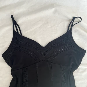 Beaded svart linne - Linne med justerbara band smyckat med pärlor! Visas på en s men passar även m. Skickas med postnords spårbara frakt för 51kr eller frimärken för 46kr. 