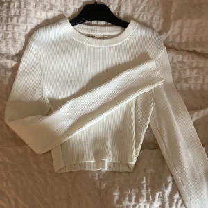 Croppad längärmad - Stretchig croppad ribbad naturvit längärmad tröja från pull and bear. Långa ärmar med en liten slit. Använda 2 gånger