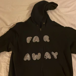 Rhinestone hoodie - Säljer min Far Away hoodie pågrund av att jag växt ur den. Tröjan är i bra skick men 3 stycken stenar saknas men dem skickas med i frakten och är enkla att sätta på. därför det låga priset. Tröjan är i storlek S. 