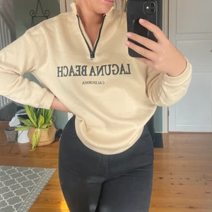 Sweatshirt  - Aldrig använd sweatshirt med dragkedja. Sweatshirten är beige med en svart text på. Materialet är super lätt och skönt på kroppen. Innersidan är fluffig och mjuk. Storleken är S.