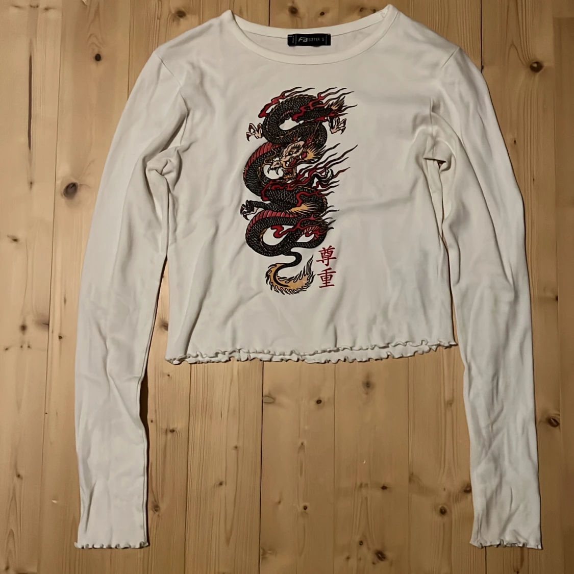 Vit långärmad tröja med en drake