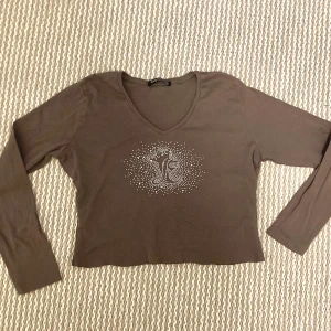y2k topp - långärmad brun tröja med tryck i glitter! köpt second hand så har avklippt söm och ser ut att ha blivit insydd i midjan nån gång tidigare, frakt ingår ej i priset :)