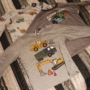 3 tröjor barn - 1 vit med fordonsmotiv storlek 92, 1 grå med racebilarmotiv storlek 86/92, 1 grå med fordonsmotiv i storlek 98. Använt skick