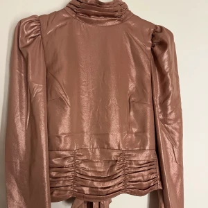 Festtopp - Super fin topp med puffärm och knyte i ryggen. Även veck på både övre och nedre del av toppen. Skulle säga att färgen är rosa, också väldigt skimrig! (se sista bilden) Verkligen så fin men kommer inte till användning💛