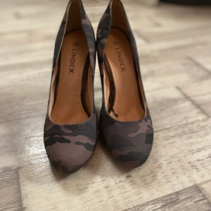 Klackskor Str 38 Militärmönster  - Klackskor med låg klack, Militär grönt mönster. Storlek 38, oanvända. Original pris 150 kr från Lindex, prislapp finns kvar. Säljer för 60 kr, frakt ingår ej. 