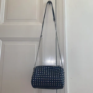 Nitväska - Säljer min absolut favoritväska 💙 Så unik och ball!! Nitväska i marinblått! Så rymlig och bra. Kan både användas som crossbody eller ha kedjan dubbel och kort över ena axeln. Lite nött på ”knäppet” o någon tagg. Annars toppenskick! Står ej något märke i.