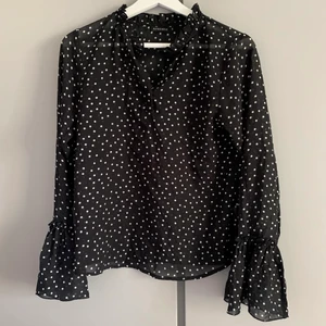 Prickig blus i svart och vitt med volang - Storlek 36