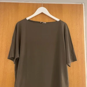 Grön kortärmad topp - Säljer en stilren brun topp med korta ärmar. Toppen har en enkel design och är gjord i ett mjukt material.