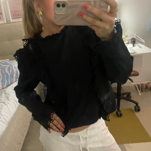 vacker svart skjorta - Säljer en elegant svart blus med vackra spetsdetaljer och volanger. Blusen har långa ärmar och en fin passform!💞