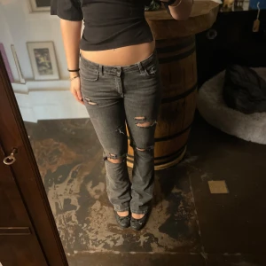 Grå Lågmidjade jeans med slitningar - Snygga grå jeans med slitningar på knäna. De har en låg midja och en bootcut-stil som ger en avslappnad look. Perfekta för en trendig outfit. Är   166 cm om passar mig bra 