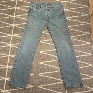 Levis 501 jeans i ljusblå denim - Säljer ett par klassiska Levis 501 jeans i ljusblå denim. De har en rak passform och är tillverkade i slitstarkt jeanstyg. Perfekta för en avslappnad stil. Ljuset får dom att se ljusgråa ut men är egentligen ljusblå, se bild 3. Storlek: W32 W34