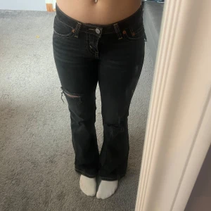 Svarta jeans med slitningar - Snygga svarta jeans från Levis med slitningar på knäna. De har en bootcut-stil och är lågmidjade. Säljer dessa då dom är för små i midjan, men längden är 32 och passar mig som är 163. Använt max 3 gånger och nypris 1200kr. Kontakta gärna om ni är intresserade, pris kan även diskuteras❣️