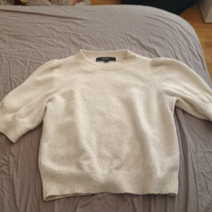 Vit tröja från Vero Moda - Säljer en stilren vit tröja från Vero Moda. Tröjan har en klassisk design med ribbade muddar vid ärmslut och nederkant. Perfekt för en enkel och elegant look.