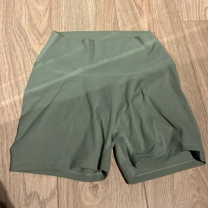 Gröna träningsshorts - Snygga gröna träningsshorts med hög midja och en tight passform. Perfekta för gymmet eller löprundan. De har en stilren design utan mönster och är gjorda i ett stretchigt syntetmaterial för bästa komfort.