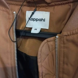 Brun bomberjacka från Kappahl - Säljer en snygg brun bomberjacka från Kappahl. Jackan har en dragkedja framtill och elastiska muddar vid ärmslut och nederkant. Perfekt för en stilren look.