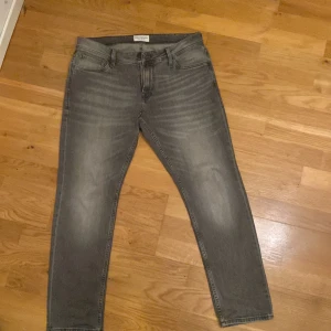 Grå jeans från Stock & Hank - Snygga grå jeans från Stock & Hank med en slim passform. De har en klassisk femficksdesign och dragkedja. Perfekta för en stilren look.