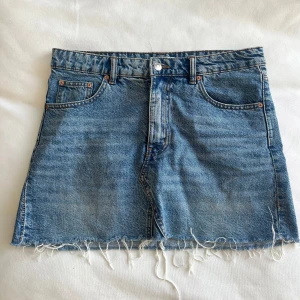 Blå jeanskjol från Gina Tricot - Säljer en snygg blå jeanskjol från Gina Tricot med rå kant och klassisk femficksdesign. Perfekt för en avslappnad stil. 🦋