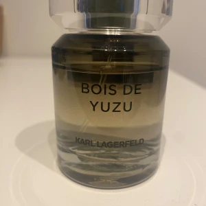 Bois de Yuzu parfym från Karl Lagerfeld - Säljer en elegant Bois de Yuzu parfym från Karl Lagerfeld. Flaskan har en stilren design med en transparent och mörkgrön ton. Perfekt för den som söker en unik och fräsch doftupplevelse.