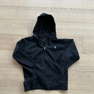 Svart huvtröja från Ralph Lauren - Säljer en stilren svart huvtröja från Ralph Lauren med dragkedja och det klassiska logotypbroderiet på bröstet. Perfekt för en avslappnad look. 🖤