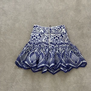 Vit och blå kjol från Zara - Snygg vit och blå kjol från Zara med ett detaljerat mönster. Kjolen har en volangdetalj som ger den extra stil och rörelse. Perfekt till sommaren !🤩🤩PRIS KAN DISKUTERAS 