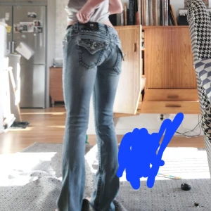 Miss Me jeans - Snygga blå jeans från Miss Me med unika detaljer och dekorationer på bakfickorna. De har en låg midja och bootcut passform. Perfekta för dig som vill ha något extra i garderoben. Midjemåttet är 35 och innerbensländen är 76