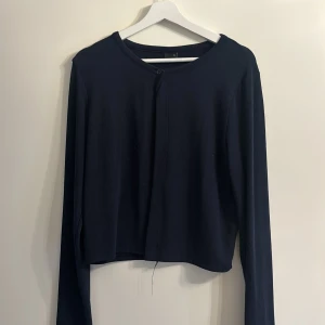 Svart kofta med knappar - Säljer en stilren svart kofta med knappar framtill. Den har långa ärmar och en enkel design som passar perfekt till olika outfits. Perfekt för kyligare dagar! Liten i storleken 