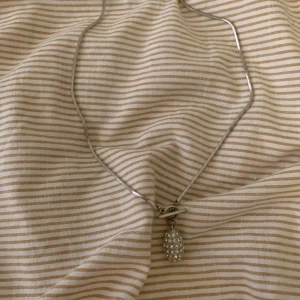 Silverhalsband med glittrigt hänge - Elegant silverhalsband med ett glittrigt ovalt hänge. Perfekt för att ge en touch av glamour till din outfit. Kedjan är tunn och smidig, vilket gör den bekväm att bära hela dagen.