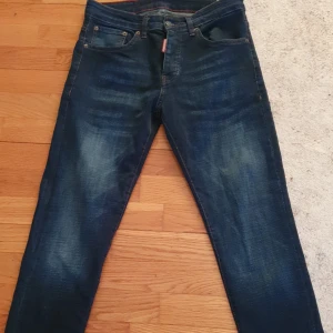 Mörkblå jeans från Dsquared2 - Snygga mörkblå jeans från Dsquared2 med klassisk femficksdesign och knappgylf. Jeansen har en diskret tvätt för en cool look och är perfekta för en stilren outfit. Märkesdetaljer synd på knappen och den röda etiketten vid fickan