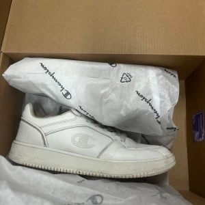 Vita sneakers från Champion - Fräscha vita sneakers från Champion med klassisk låg profil och rund tå. Skorna har snörning, diskret Champion-logga på sidan och är tillverkade i syntetmaterial med textilfoder. Perfekta för en clean och sportig look.