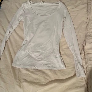Vit långärmad topp med rund hals - En basic vit långärmad topp från H&M med rundad halsringning. Modellen är figurnära och passar perfekt till lager-på-lager eller som enkel vardagstopp. Tillverkad i mjuk bomull för en skön känsla hela dagen.