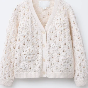 Beige stickad kofta med blommor - Superfin beige stickad kofta från Zara med virkade blommor och v-ringning. Koftan har knappar framtill och ett luftigt, mönstrat stickat material som ger en söt och trendig look. Perfekt att slänga över en topp för extra stilpoäng.
