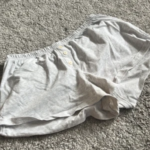 Grå bomullsshorts Brandy Melville - Lätta och mjuka grå shorts från Brandy Melville i bomull. De har elastisk midja och tre knappar framtill för en chill look. Perfekt hemmaplagg och köpt för 200kr😇