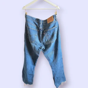 Levi's 582 W33 L34 - Klassiska blå Levi's 582 med rak passform och råa, fransiga benslut. Jeansen har fem fickor, knappgylf och tydlig vintagekänsla. Perfekta för dig som gillar en avslappnad och tidlös look.