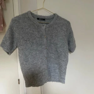 Grå kofta från Gina Tricot XS - Mysig grå kofta från Gina Tricot i storlek XS. Kortärmad och stickad med fluffig textur, rund halsringning och silvriga knappar framtill. Perfekt för sommar och höst, men även vinter med en kofta på. Den är i jätte bra skick , knappt använd. Ny pris ca 300kr. Priset går att diskuteras vid snabbt köp