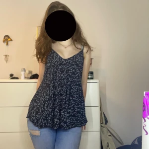 Mörkblå blommig linnetopp - Säljer en flowy mörkblå linnetopp med små vita blommor. Toppen har v-ringning, tunna axelband och en avslappnad passform. Har köpt på en marknad i Marseille och är super skön att ha på semester speciellt om det är varmt! ❤️❤️