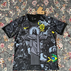 Nike Brasil svart fotbollströja - Unik svart Brasil-fotbollströja från Nike med detaljerat grafiskt tryck av Kristusstatyn, kyrkor och brasilianska symboler. Broderat CBF-märke och Nike-logga i gult. Korta ärmar och lätt, ventilerande material. Perfekt för dig som vill sticka ut på planen eller läktaren.
