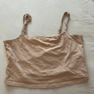 Beige linnetopp från 157, storlek S - Enkel och stilren beige linnetopp från 157 med smala axelband. Toppen är croppad och tillverkad i mjuk bomullsmix med lite stretch för skön passform. Perfekt till jeans eller kjol när du vill ha en clean och avslappnad look.