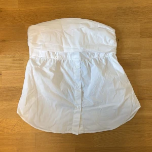 Vit bandeau topp från Zara - Säljer en söt vit bandeau topp från Zara. Väldigt populär i skjortmaterial❣️