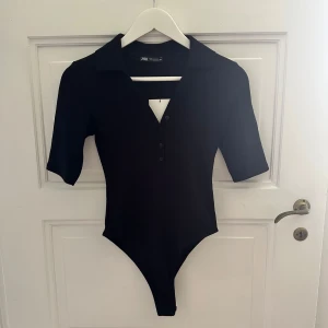 Svart body från Zara - Svart body från Zara med  krage och v-ringning. Aldrig använd och med prislapp kvar. 