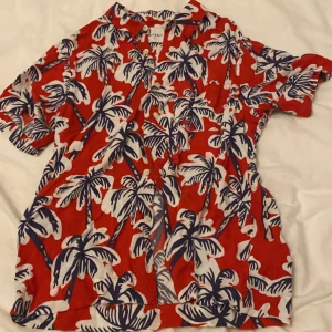 Röd mönstrad skjorta från Vailent - Säljer en röd skjorta från Vailent med kort ärm och knappar framtill. Skjortan har ett tropiskt mönster med vita och blå palmer, perfekt för sommarens chill dagar💗 Använt några gånger, pris går att diskutera💗