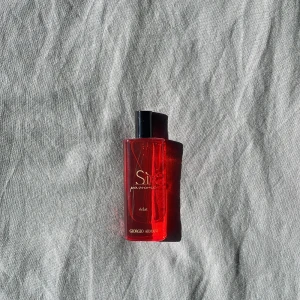 Sì Passione Éclat Eau de Parfum från Giorgio Armani - Säljer en elegant och förförisk parfym, Sì Passione Éclat från Giorgio Armani. Flaskan är i en djärv röd färg med en stilren svart kork. Perfekt för den som vill ha en doft som utstrålar passion och elegans.
