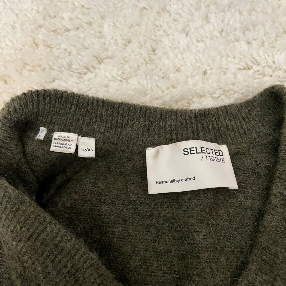 Säljer en stilren grön tröja från Selected Femme i mjuk ull. Tröjan har en v-ringad design och långa ärmar, perfekt för kyligare dagar. Den är både bekväm och snygg, ett måste i garderoben! 🍃. Neuletakit & Villapaidat.