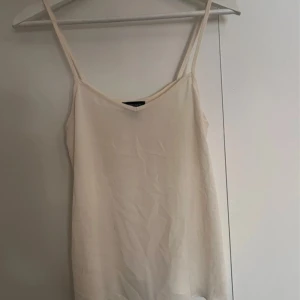 Vit linnetopp från Topshop - Säljer en stilren vit linnetopp från topshop med smala axelband. Perfekt för varma sommardagar eller som ett basplagg i garderoben. Enkel och tidlös design som passar till det mesta.