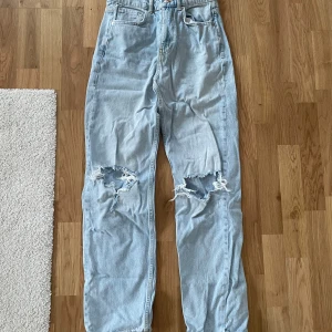Ljusa jeans med slitningar - Snygga ljusblå jeans från Gina Tricot med coola slitningar på knäna. De har en hög midja och en straight passform som ger en avslappnad look. Perfekta för en trendig stil!